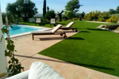 a pool with two lounge chairs next to a green lawn at Villa exclusiva con piscina privada, La Tina Golf in Arcos de la Frontera