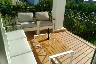 a balcony with two chairs and a table with a bottle of wine at Villa exclusiva con piscina privada, La Tina Golf in Arcos de la Frontera