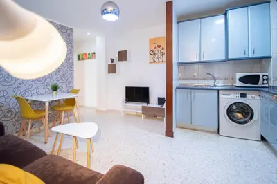 a kitchen and living room with a washing machine and a table at Esencia de Cádiz Entre la Viña y el mercado in Cádiz