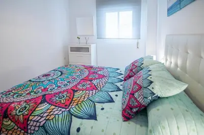 a bed with colorful pillows on it in a bedroom at Esencia de Cádiz Entre la Viña y el mercado in Cádiz