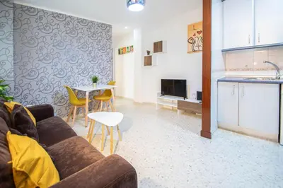a living room with a couch and a table and a kitchen at Esencia de Cádiz Entre la Viña y el mercado in Cádiz