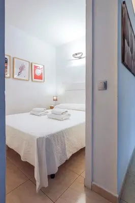 a white room with a bed with white sheets at Un respiro en cádiz playa victoria 1 hab y salón con sofa cama in Cádiz