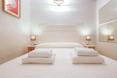 a white bedroom with two beds and two lamps at Un respiro en cádiz playa victoria 1 hab y salón con sofa cama in Cádiz