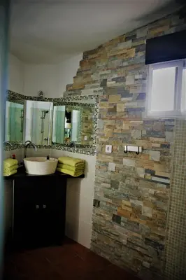 a bathroom with a sink and a stone wall at Cortijo Flamingos in Chiclana de la Frontera