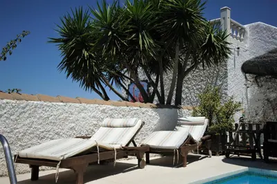 a group of lounge chairs next to a swimming pool at Cortijo Flamingos in Chiclana de la Frontera