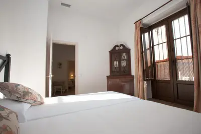 a bedroom with a white bed and a door and a room at Patios de la Riva in Jerez de la Frontera