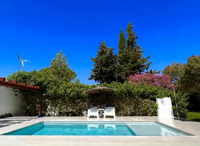 a swimming pool with two chairs and an umbrella at La Casita de Los Alambiques in Chiclana de la Frontera