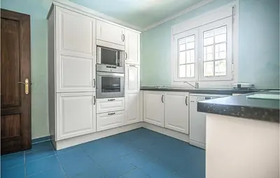 a kitchen with white cabinets and a blue tile floor at Lovely Home In Chiclana De La Fronter in Cádiz