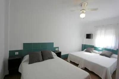 a bedroom with two beds and a ceiling fan at Apartamento Mercedes Céntrico Playa in Sanlúcar de Barrameda