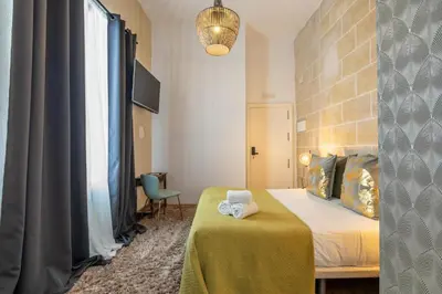 a bedroom with a bed with a green blanket and a lamp at Catedral Suites Jerez in Jerez de la Frontera