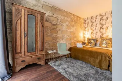 a bedroom with a bed and a dresser and a chair at Catedral Suites Jerez in Jerez de la Frontera