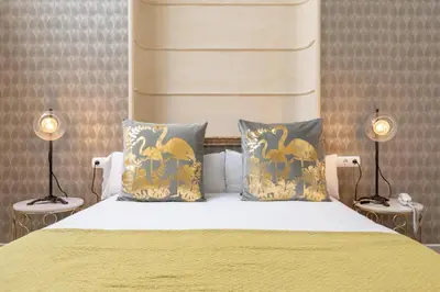 a bedroom with a yellow bed with two lamps at Catedral Suites Jerez in Jerez de la Frontera