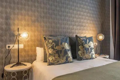 a bedroom with a bed with blue and white pillows at Catedral Suites Jerez in Jerez de la Frontera