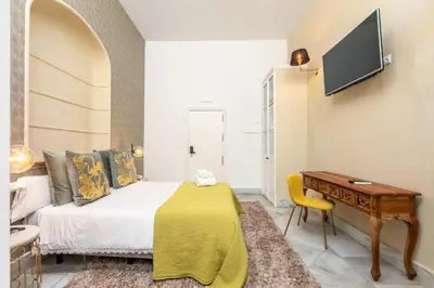 a bedroom with a bed and a desk and a television at Catedral Suites Jerez in Jerez de la Frontera