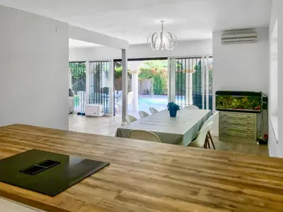 a kitchen and dining room with a table and a television at Villa Alamos Jerez I Piscina Salada Climatizada I BBQ I Jardines I 850m2 in Jerez de la Frontera