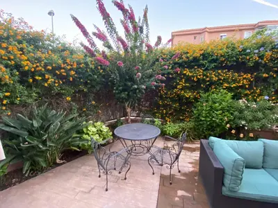a patio with a table and chairs and flowers at Apartamento jardin Sanlucar in Sanlúcar de Barrameda