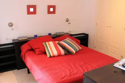 a bedroom with a red bed with two pillows on it at Apartamento jardin Sanlucar in Sanlúcar de Barrameda