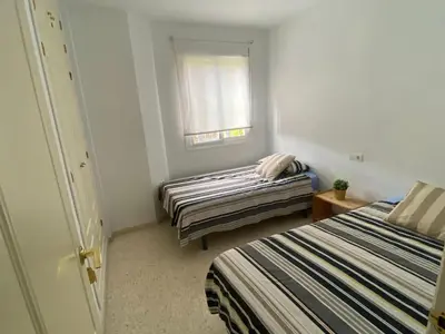 a small room with two beds and a window at Apartamento jardin Sanlucar in Sanlúcar de Barrameda