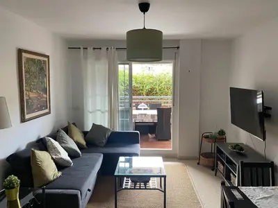 a living room with a blue couch and a tv at Apartamento jardin Sanlucar in Sanlúcar de Barrameda