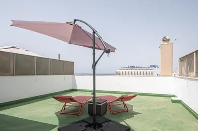 a patio with two chairs and an umbrella on a roof at Loft Space - Time in Cádiz in Cádiz