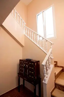 a staircase with a wooden chest next to a window at Villas Aloha Valdelagrana in El Puerto de Santa María