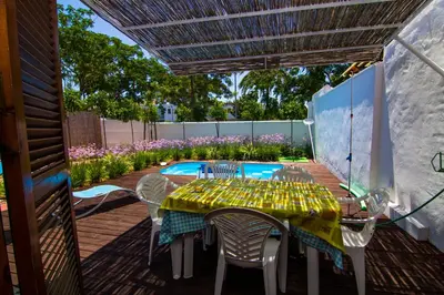 a patio with a table and chairs and a pool at Villas Aloha Valdelagrana in El Puerto de Santa María