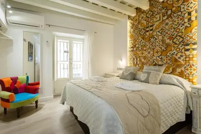 a bedroom with a large bed and a colorful chair at Apartamentos LOTO y LIZ by Cadiz4Rentals in Cádiz