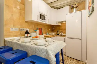 a kitchen with a table and a white refrigerator at Apartamentos LOTO y LIZ by Cadiz4Rentals in Cádiz