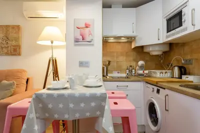 a kitchen with a table and pink stools at Apartamentos LOTO y LIZ by Cadiz4Rentals in Cádiz