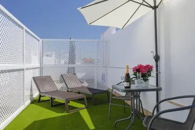 a balcony with two chairs and a table and an umbrella at Apartamentos LOTO y LIZ by Cadiz4Rentals in Cádiz