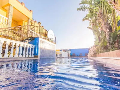 a swimming pool at a resort with palm trees at Oasis de Cádiz in Conil de la Frontera