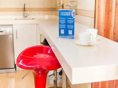 a red stool sitting at a kitchen counter with cups at Oasis de Cádiz in Conil de la Frontera