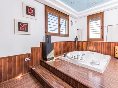 a large bathroom with a tub and wooden floors at Oasis de Cádiz in Conil de la Frontera