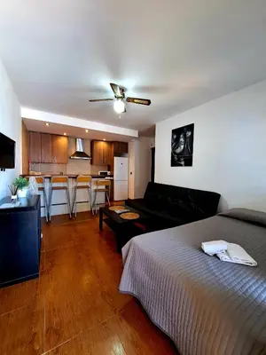 a bedroom with a bed and a couch and a kitchen at Oasis de Cádiz in Conil de la Frontera