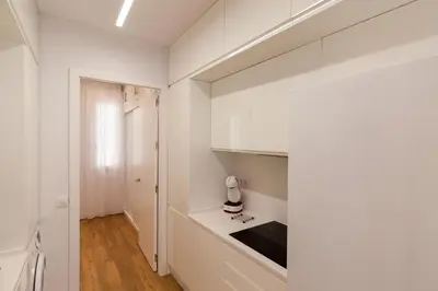 a white kitchen with white cabinets and a table at Apartamento Barrocal in Cádiz