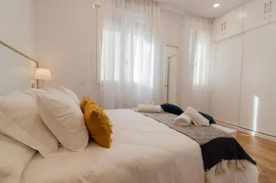 a white bedroom with a large white bed with pillows at Apartamento Barrocal in Cádiz