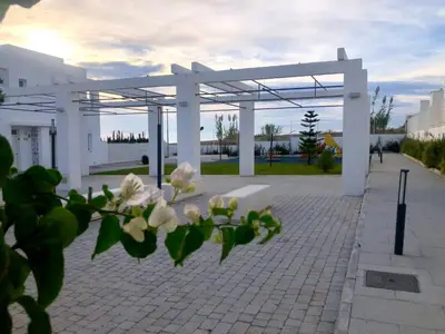 a pavilion with white flowers in front of a building at GATU PREMIUM Conil Sunset house con piscina, 3 dormit, 3 baños, jardín privado , wifi y parking, preferente mayores de 21 años y familias in Conil de la Frontera