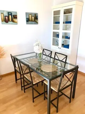 a glass table with chairs and a vase of flowers at GATU PREMIUM Ático Parra, parking, piscina común, terraza, wifi , 