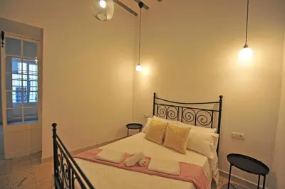a bedroom with a bed with two chairs and two lights at Apartamentos Casa Rosaleda in Jerez de la Frontera