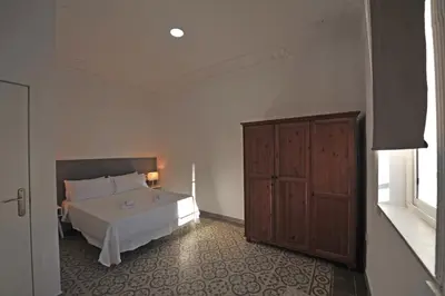 a bedroom with a white bed and a wooden cabinet at Apartamentos Casa Rosaleda in Jerez de la Frontera