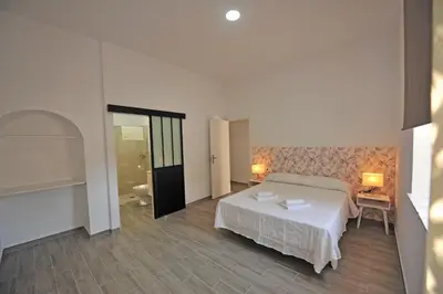 a bedroom with a white bed and a bathroom at Apartamentos Casa Rosaleda in Jerez de la Frontera
