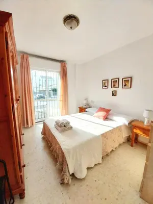 a bedroom with a large bed with white sheets at Beach Apartment La Costilla - Free Parking in Rota