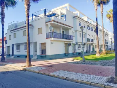 a white building with palm trees in front of it at Beach Apartment La Costilla - Free Parking in Rota