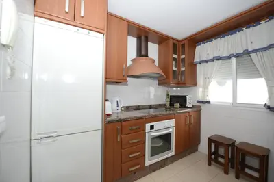 a kitchen with wooden cabinets and a stove top oven at CASA PALACIO LAS PALOMAS in Sanlúcar de Barrameda