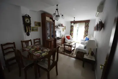 a living room with a table and chairs and a clock at CASA PALACIO LAS PALOMAS in Sanlúcar de Barrameda