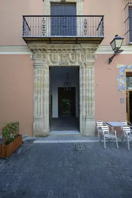 a building with a balcony and a table and chairs at CASA PALACIO LAS PALOMAS in Sanlúcar de Barrameda