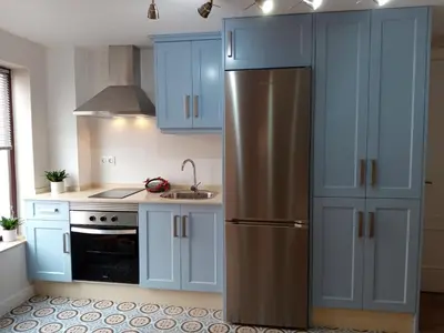 a kitchen with blue cabinets and a stainless steel refrigerator at Estudio jacuzzi Luz de Jerez in Jerez de la Frontera