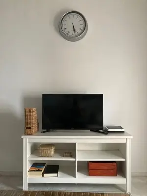 a white entertainment center with a tv and a clock on the wall at El Envero Apartamento in Jerez de la Frontera