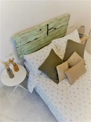 a bed with a wooden headboard and pillows and a table at El Envero Apartamento in Jerez de la Frontera