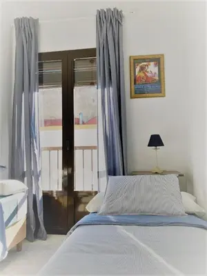 a bedroom with a bed with blue curtains and a window at El Envero Apartamento in Jerez de la Frontera